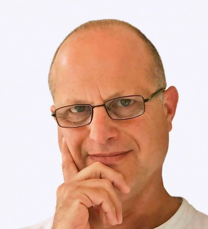 Un hombre que lleva gafas tiene la mano en la barbilla.
