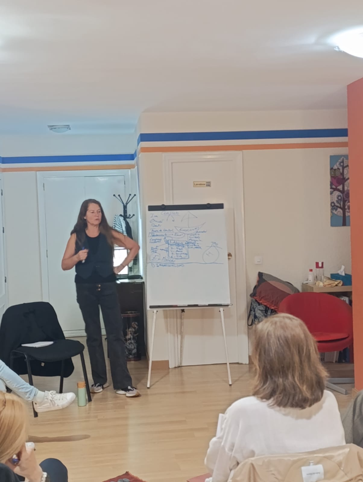 Una mujer está dando una presentación a un grupo de personas en una habitación.
