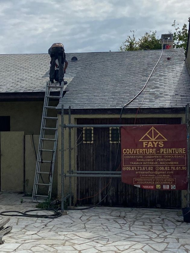 Ouvrier sur un toit qui applique un traitement sur un toit en ardoise