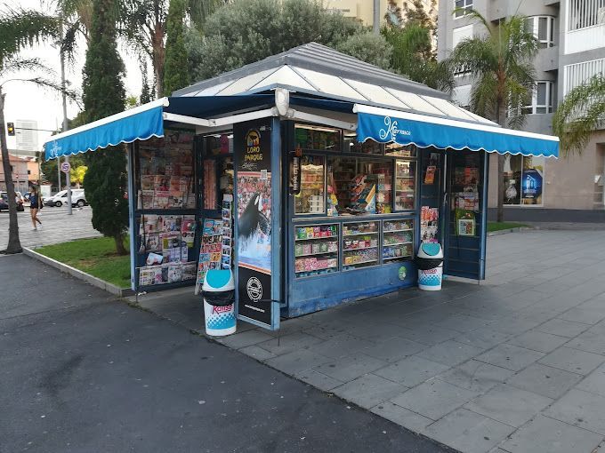 Un quiosco azul con un toldo azul está sentado en una acera.