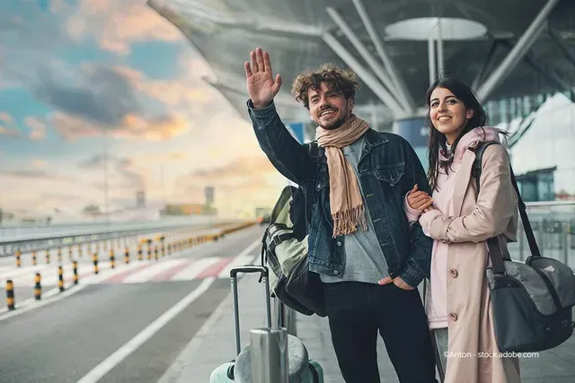 Ein junges Paar am Flughafen ruft nach einem freien Taxi