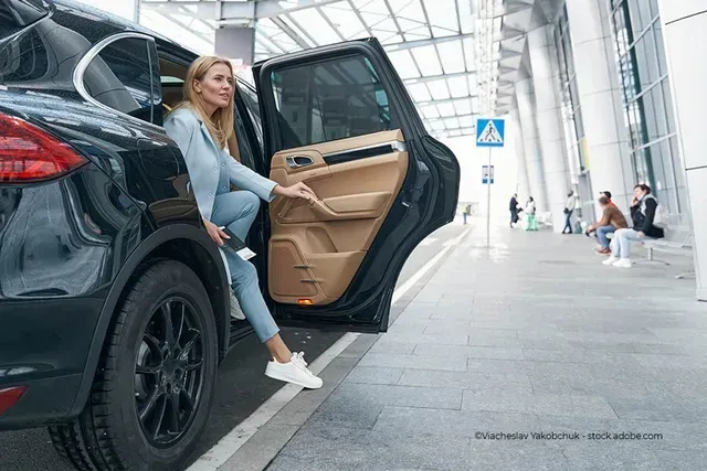 Eine junge Frau steigt aus einem Taxi aus an einem Messegelände