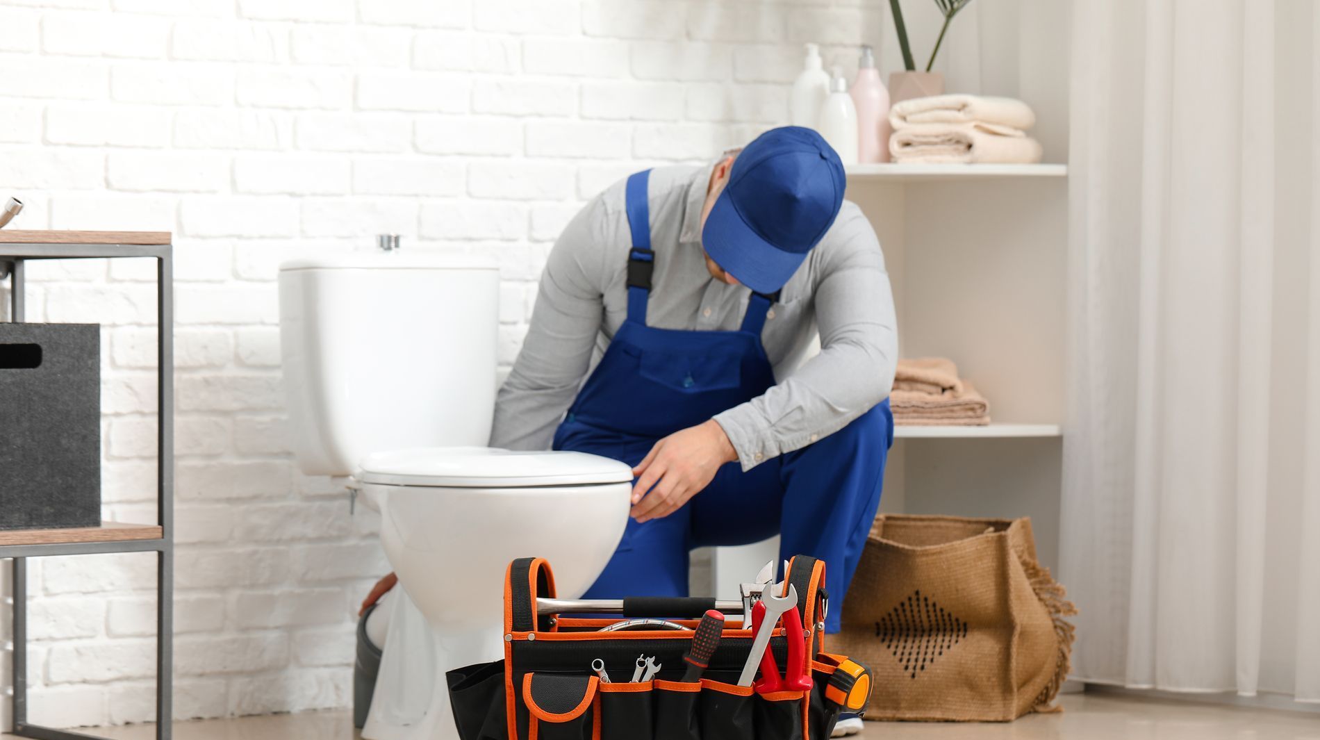 Un plombier répare des toilettes dans une salle de bain.