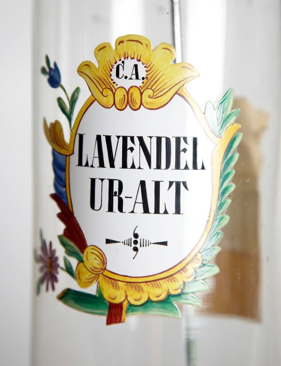 Etikett auf einer Glasflasche mit der Aufschrift „Lavendel Ur-Alt“. Verziert mit floralen und kunstvollen Mustern sowie goldenen, blauen und roten Akzenten.
