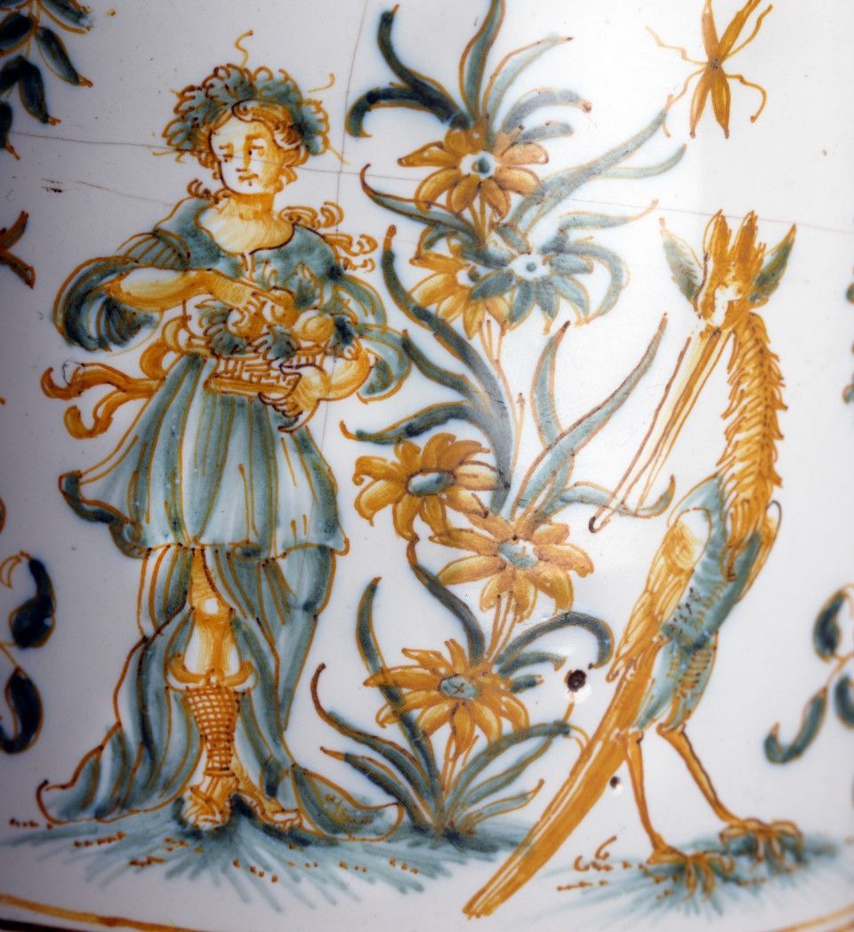 Bemalte Keramik mit einer Figur, die Blumen hält, und einem Wesen neben gelben Blumen.