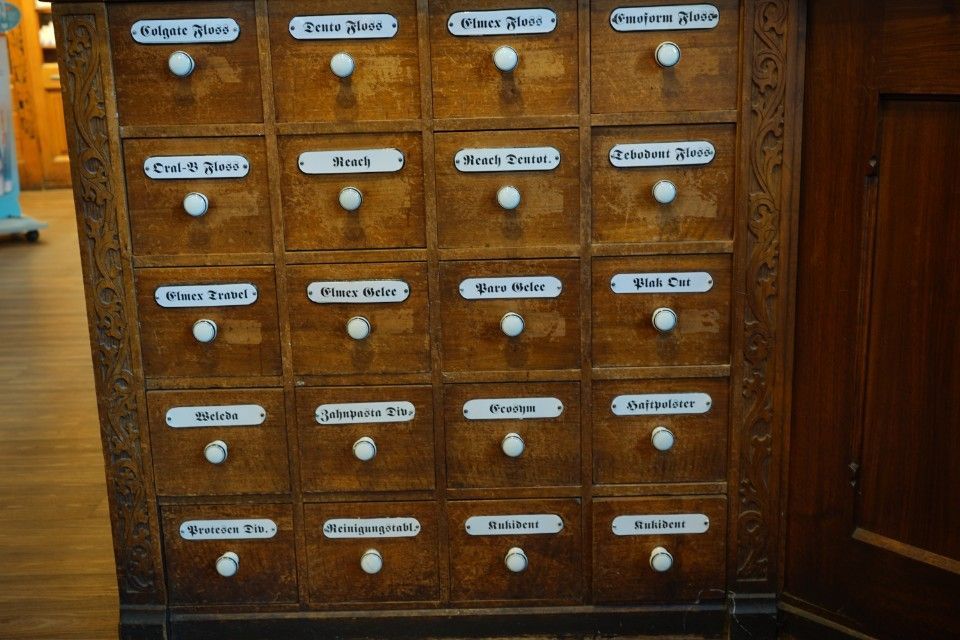 Hölzerner Apothekerschrank mit vielen beschrifteten Schubladen.