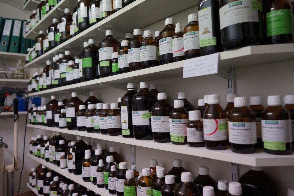 Regale voller brauner Glasflaschen, vermutlich Apothekenartikel, mit weissen Etiketten.