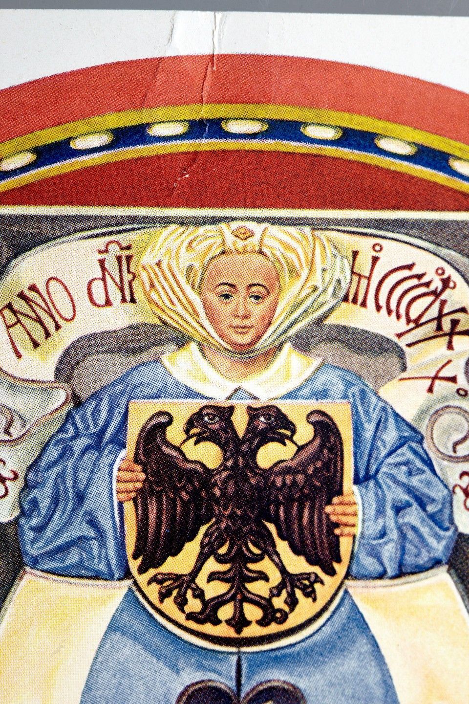 Eine Frau in Blau hält einen Schild mit einem doppelköpfigen Adler unter einem rot-goldenen Banner, umgeben von Text.