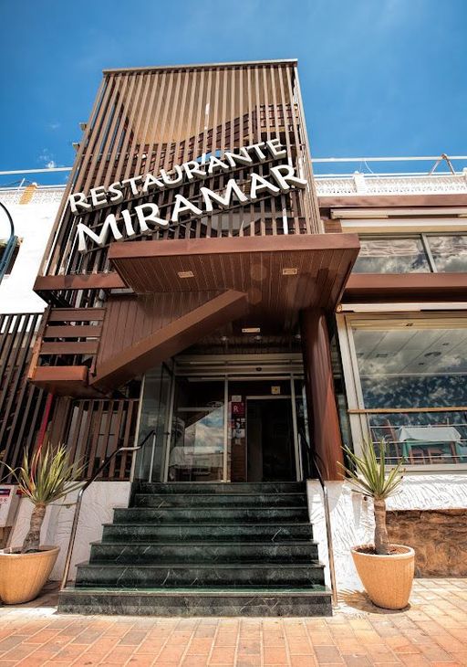 Entrada del restaurante Miramar con escalones verdes, fachada de madera y cielo azul.
