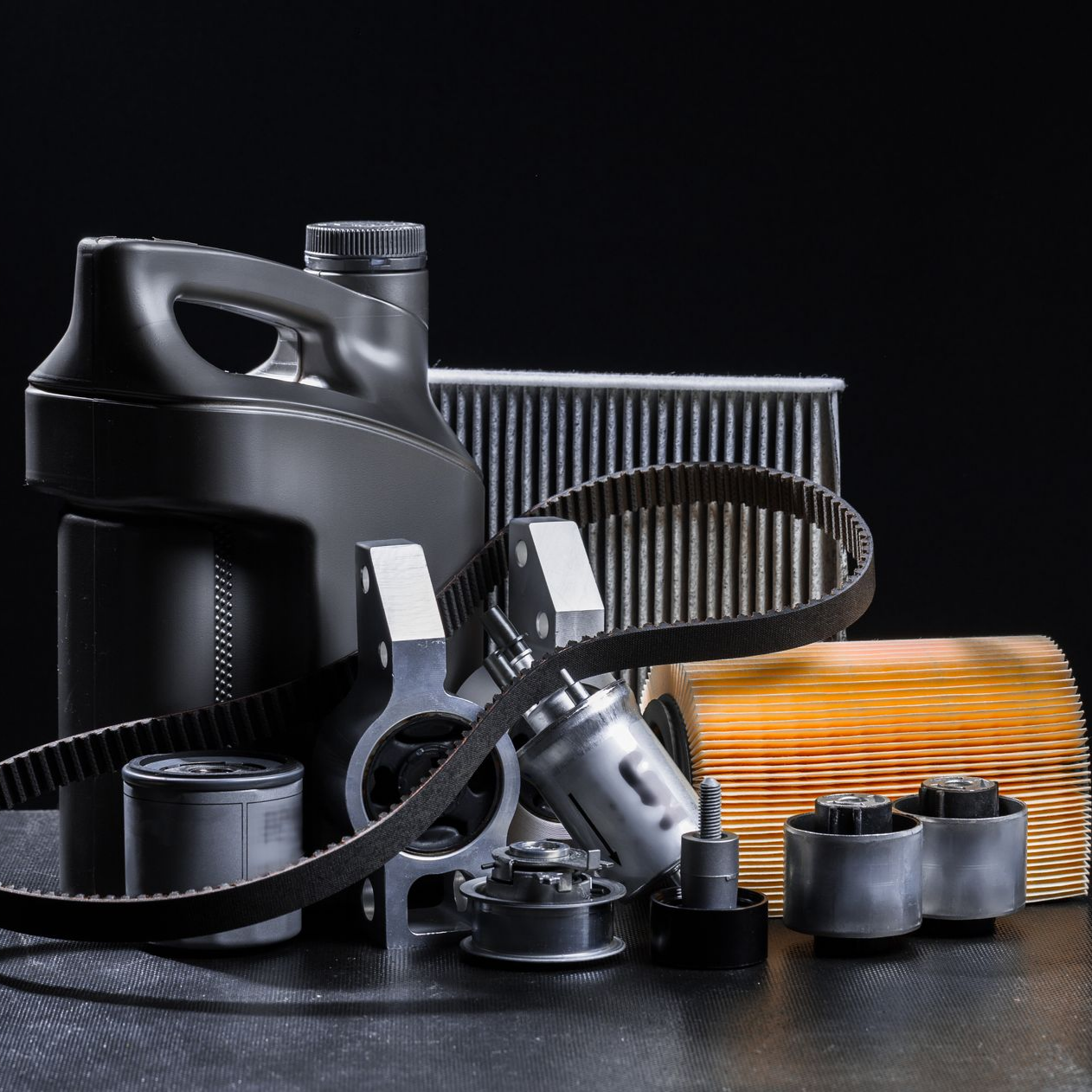 Pièces et filtres de moteur de voiture noirs assortis, disposés sur une surface sombre et réfléchissante.