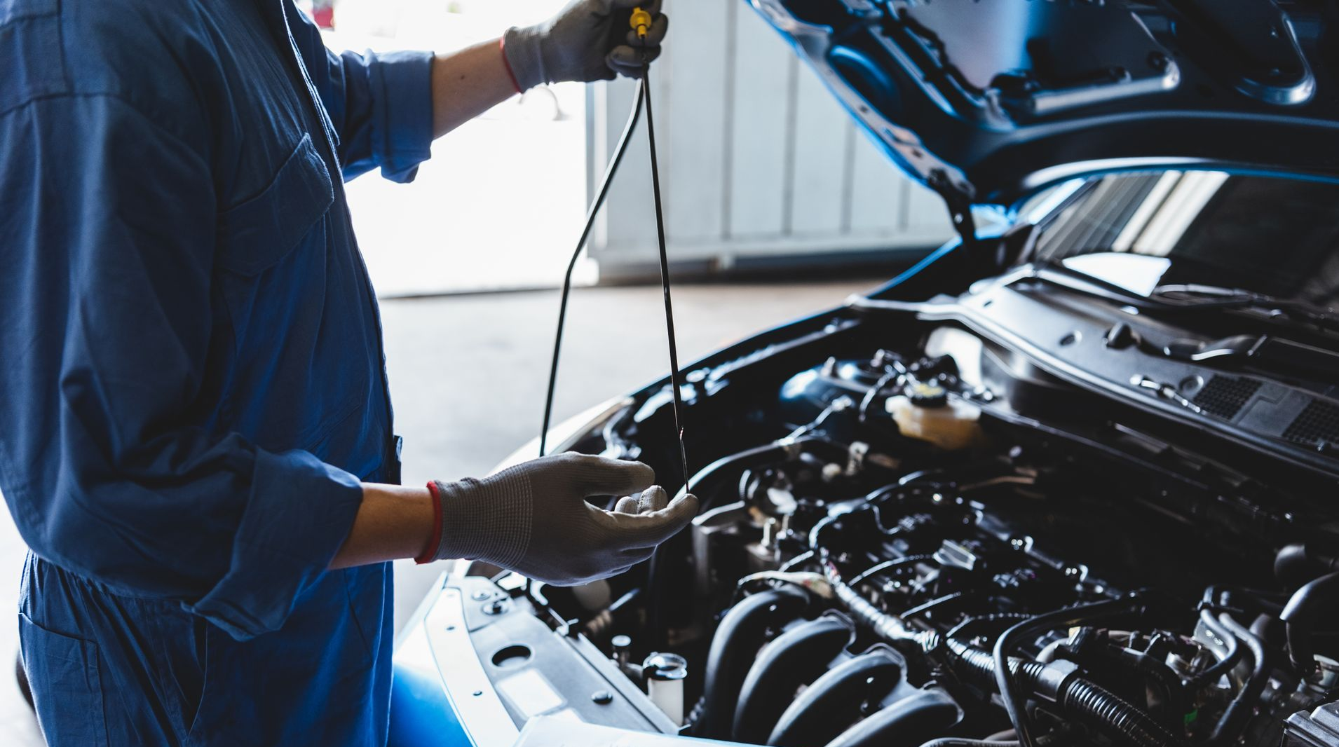 Un mécanicien inspecte le moteur d'une voiture, capot ouvert, dans un garage.