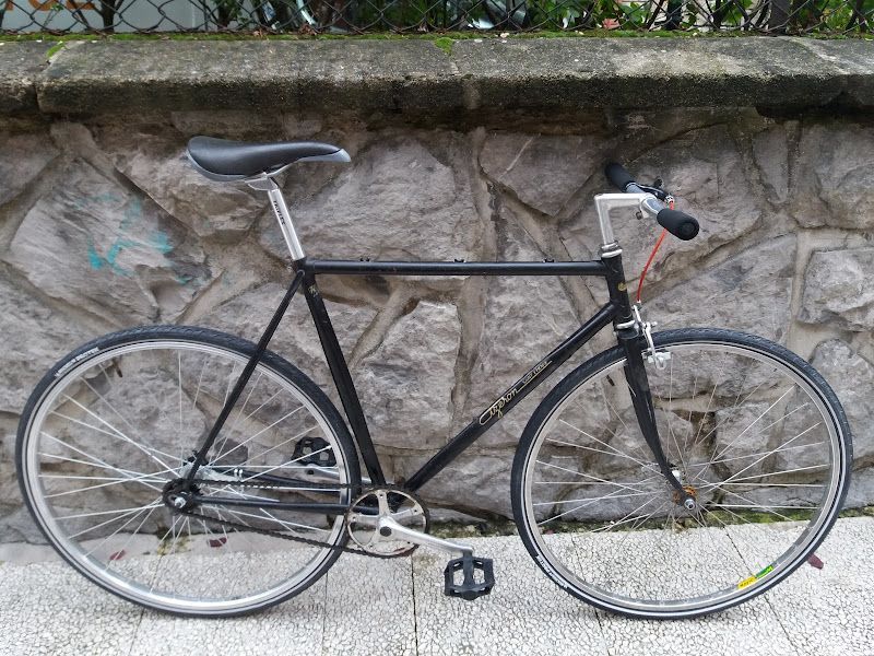 Una bicicleta negra está estacionada frente a un muro de piedra.