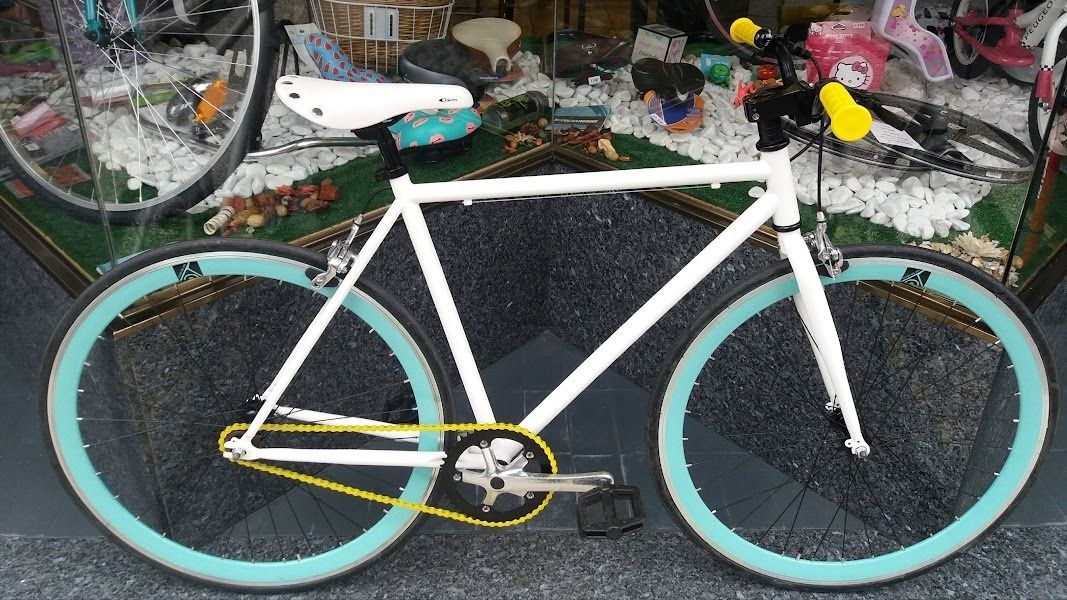 Una bicicleta blanca con llantas azules y una cadena amarilla