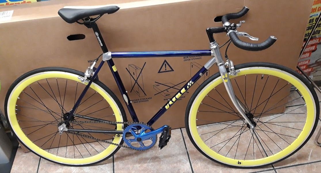 Una bicicleta azul y amarilla está delante de una caja de cartón.