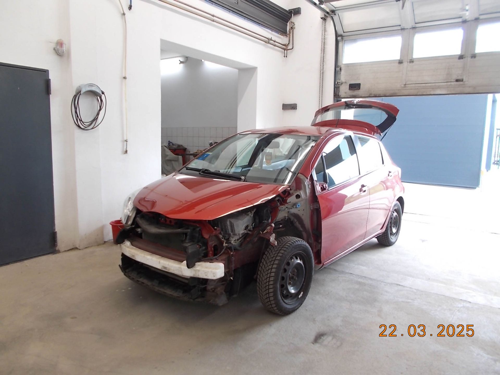 Ein rotes Auto steht mit offenem Kofferraum in einer Garage.