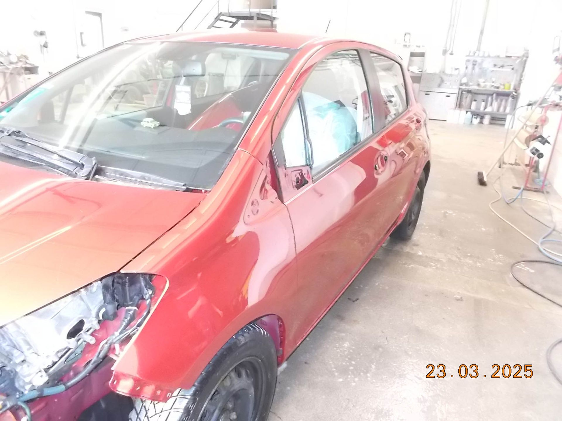 Ein rotes Auto steht mit offener Tür in einer Garage.