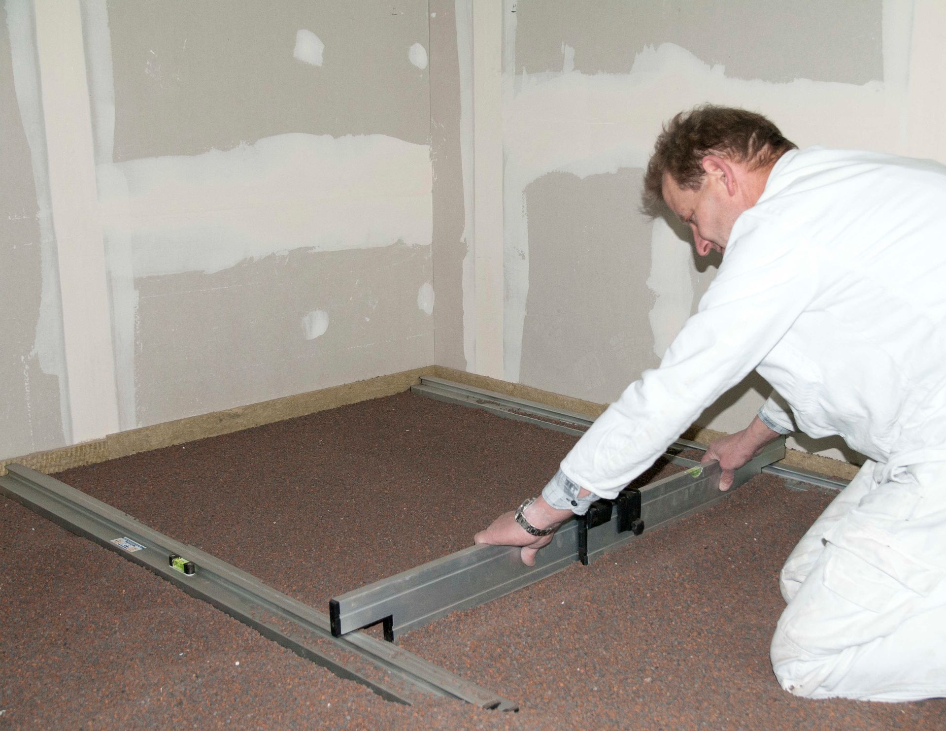 Ein Mann zieht Sand glatt mit einer verstellbaren Abziehlatte