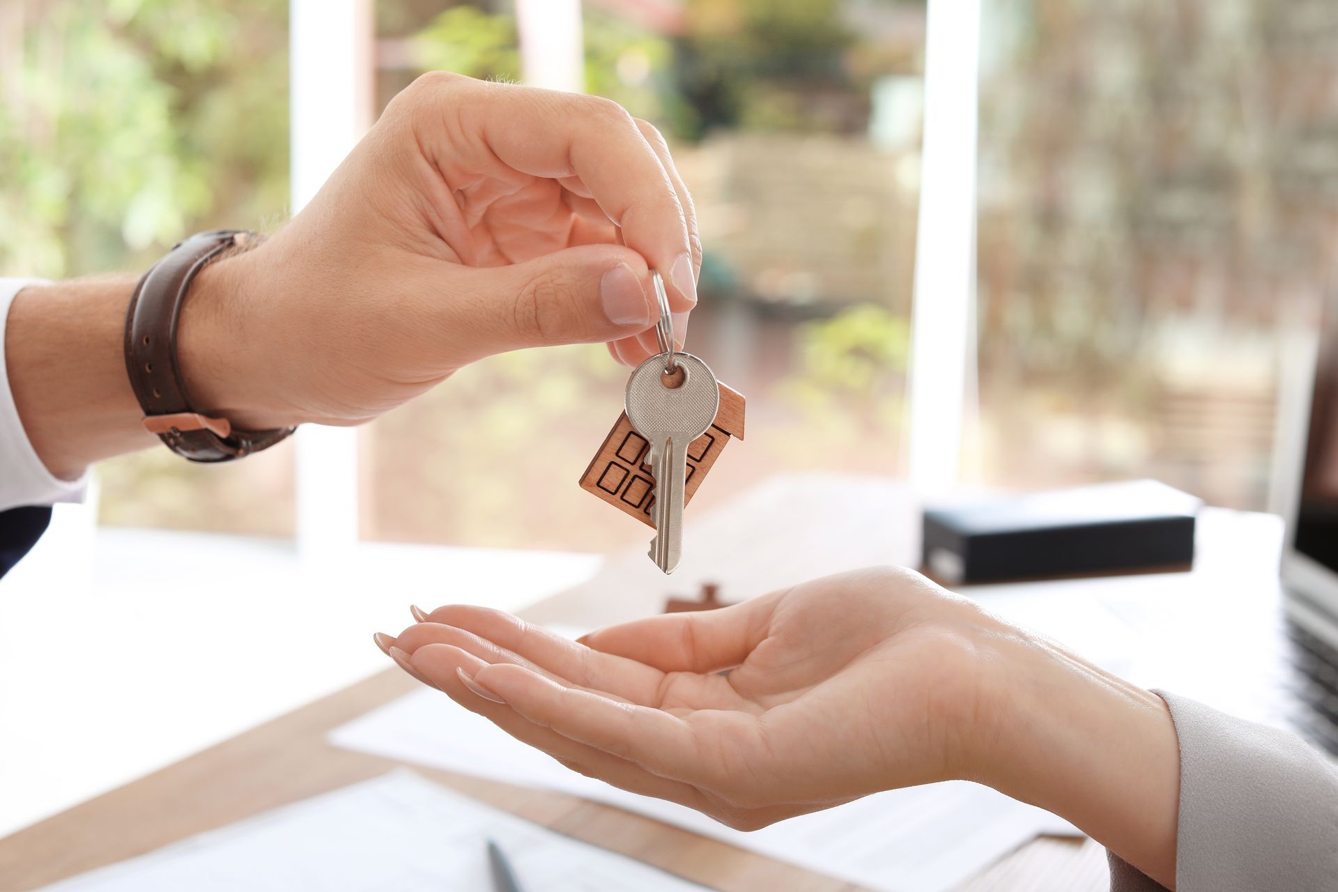 Persona entregando las llaves de su casa a la mano abierta de otra persona.