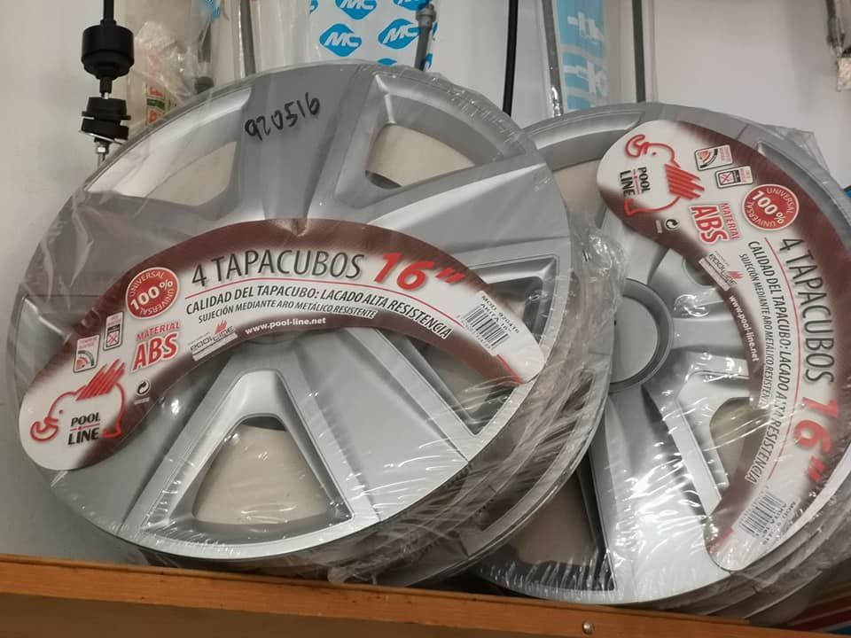 Dos cubiertas de ruedas plateadas están colocadas una encima de la otra en un estante.