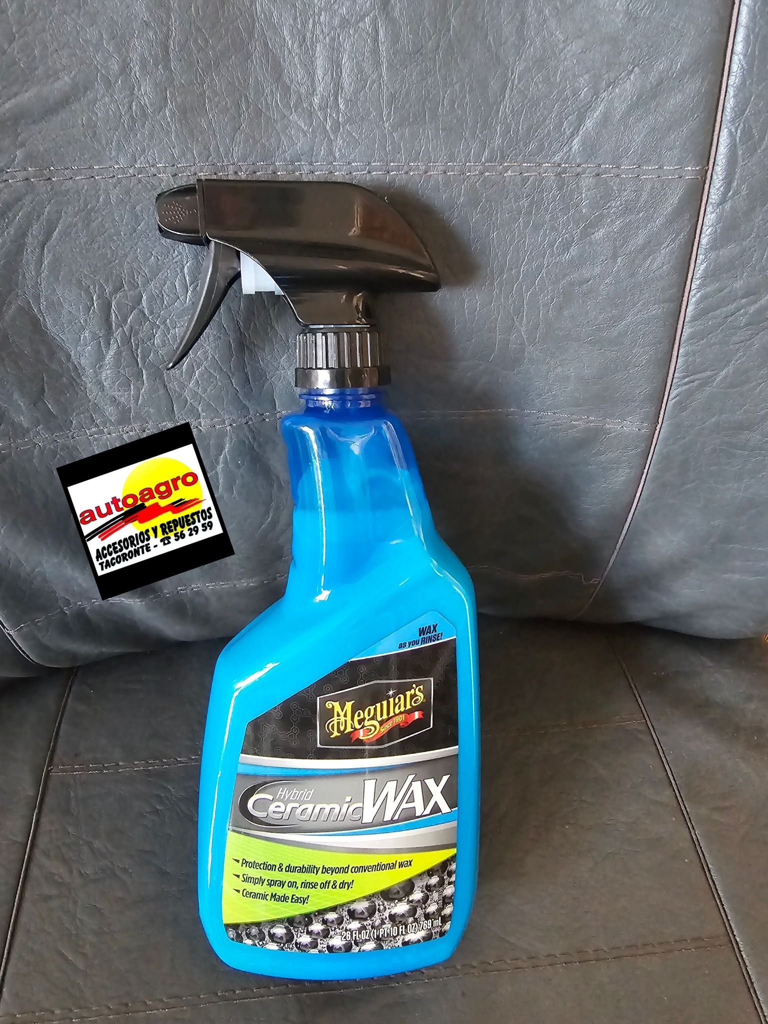 Una botella de limpiador Meguiar's Max está sentada en un sofá de cuero.