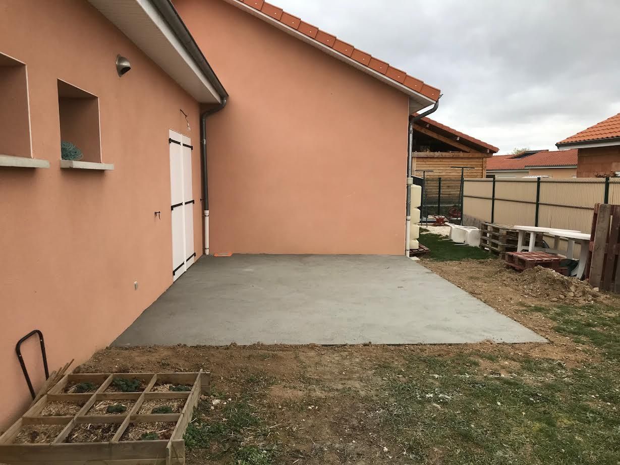 Terrasse arrière attenante à une maison couleur pêche, avec pelouse, clôture et petit potager.