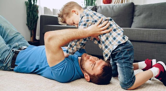 Un hombre está acostado en el suelo con su hijo.