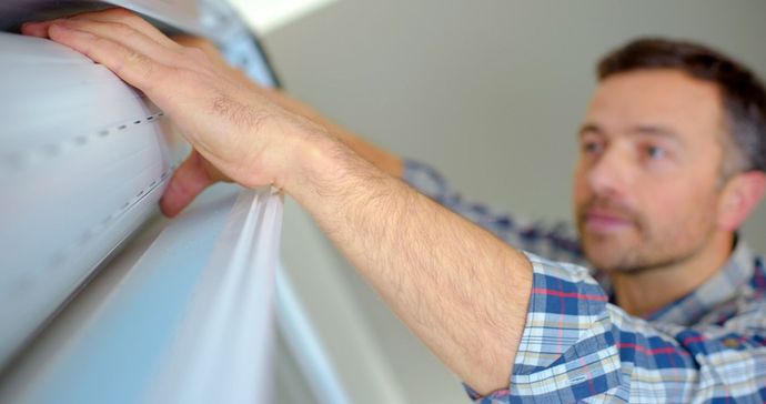 Un hombre sostiene un rollo de papel tapiz en una pared.