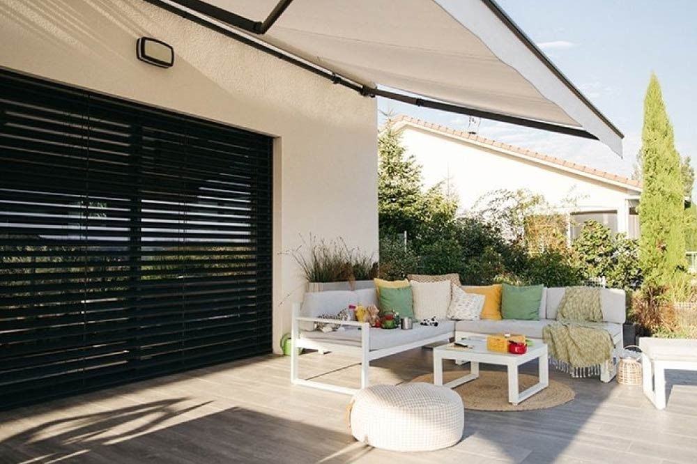 Un patio con un sofá y una mesa bajo un toldo.
