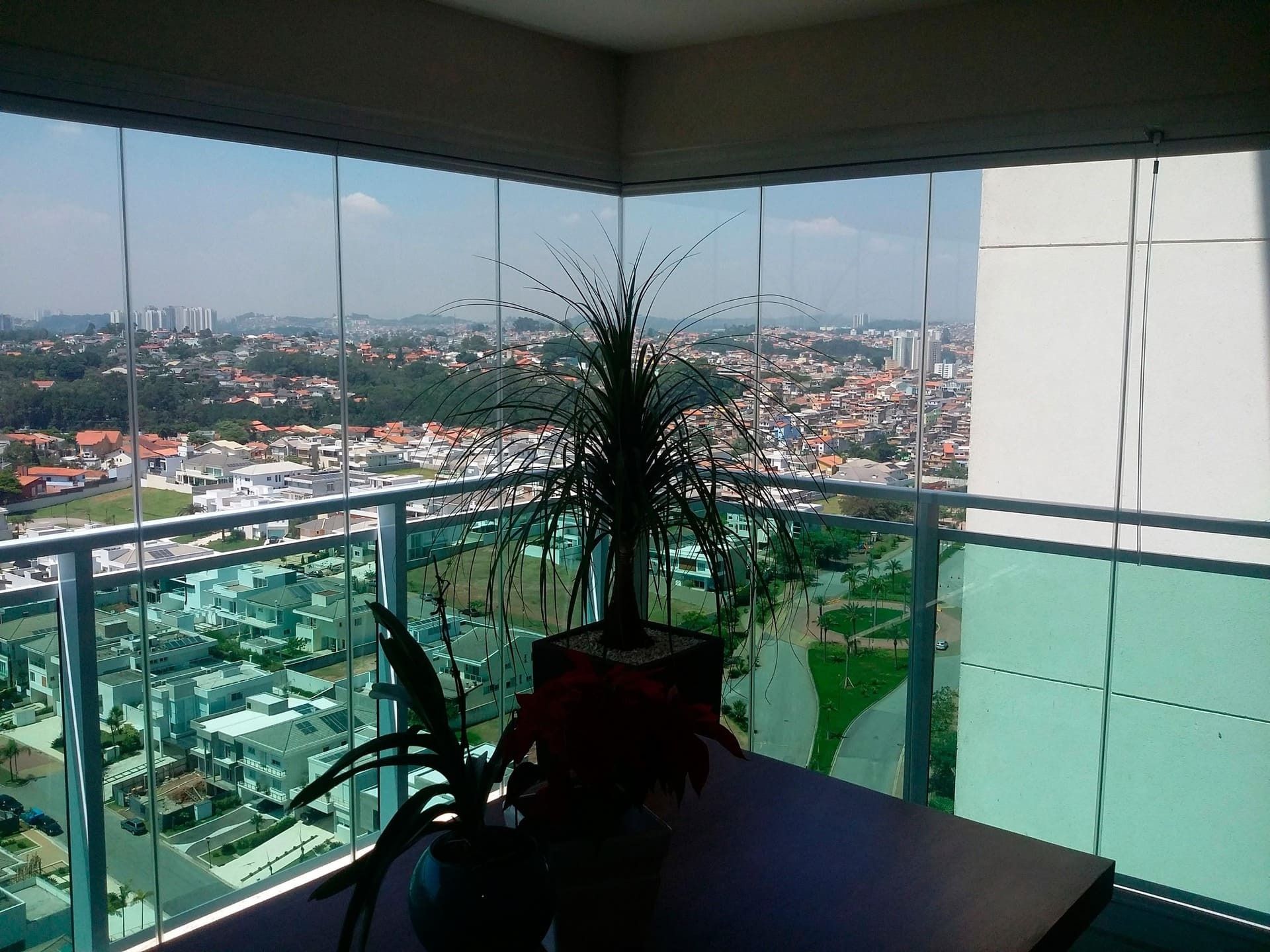 Un balcón con vista a una ciudad y una planta en él.
