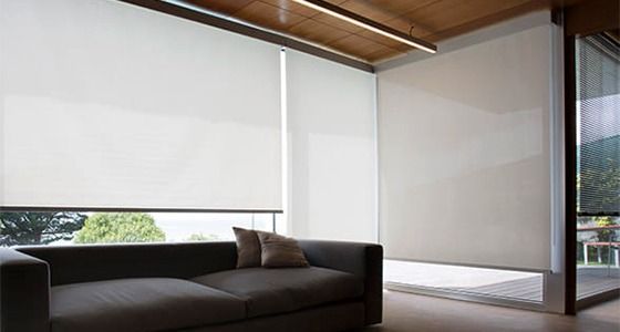 Una sala de estar con un sofá y persianas en las ventanas.