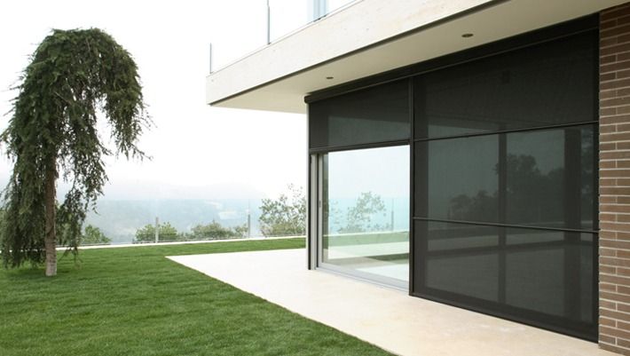 Una casa grande con una puerta corrediza de vidrio y un árbol al fondo.
