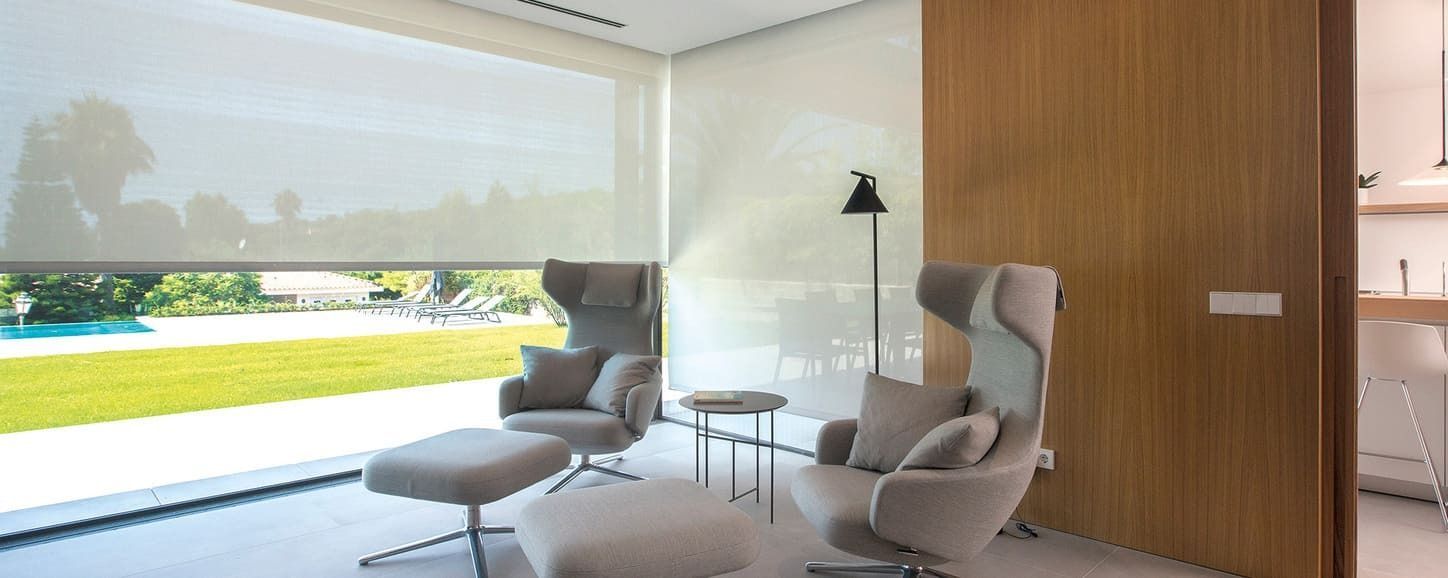 Una sala de estar con una silla y una otomana y una ventana grande.