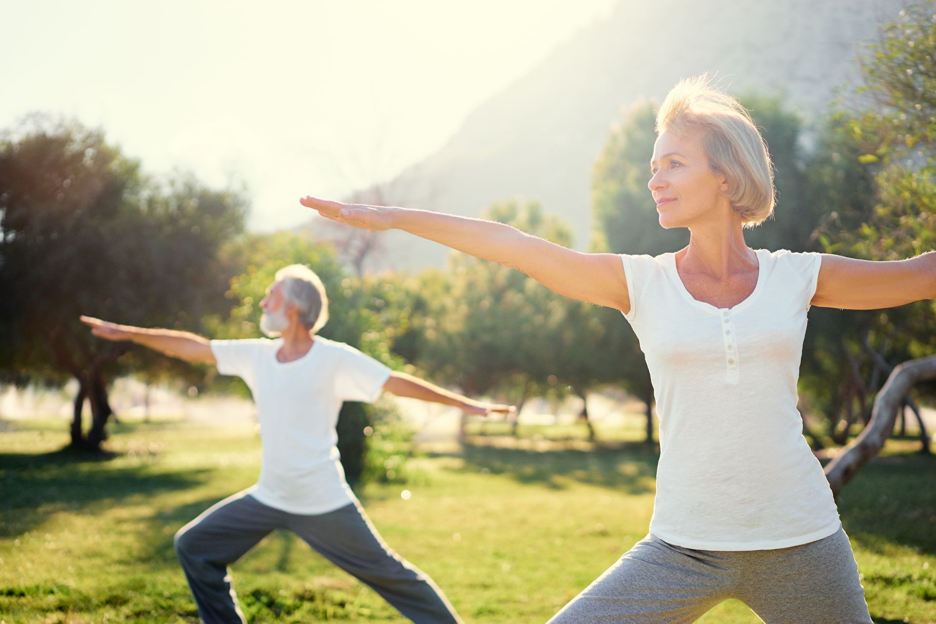 Femme et homme en position de yoga avec un paysage montagneux en arrière-plan