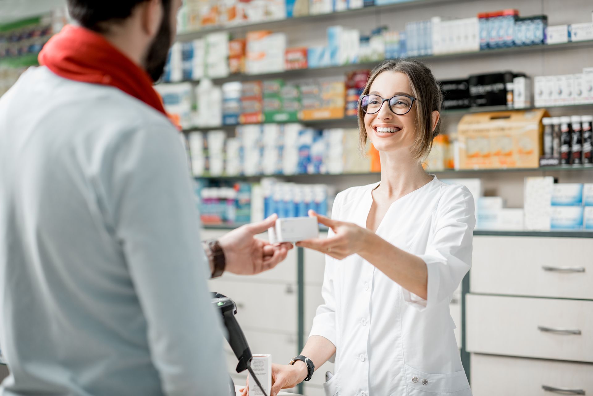 Pharmacienne souriante qui tend une boîte de médicaments à un client
