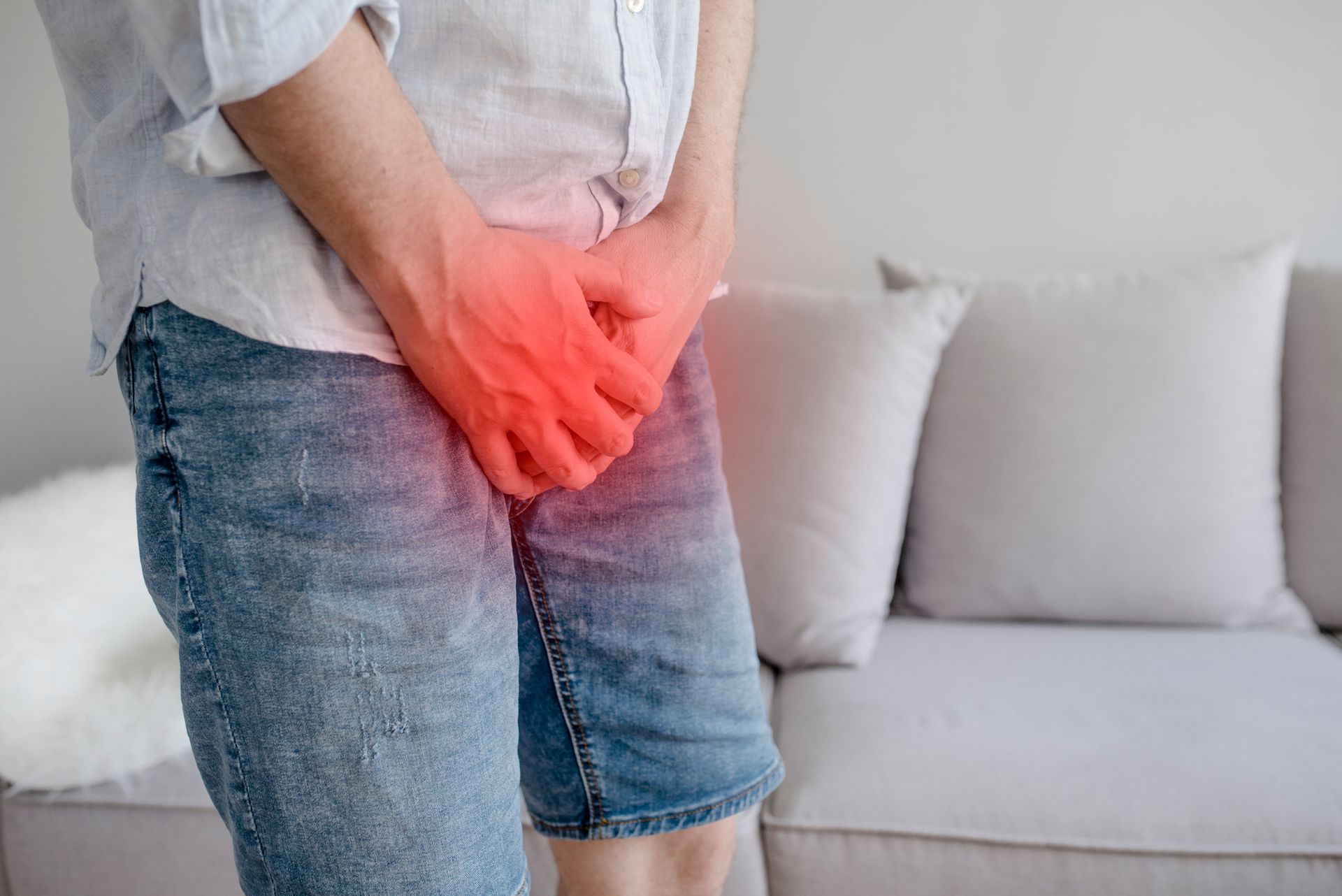 Homme en short en jean qui cache son entrejambe, zone recouverte d'un halo rouge