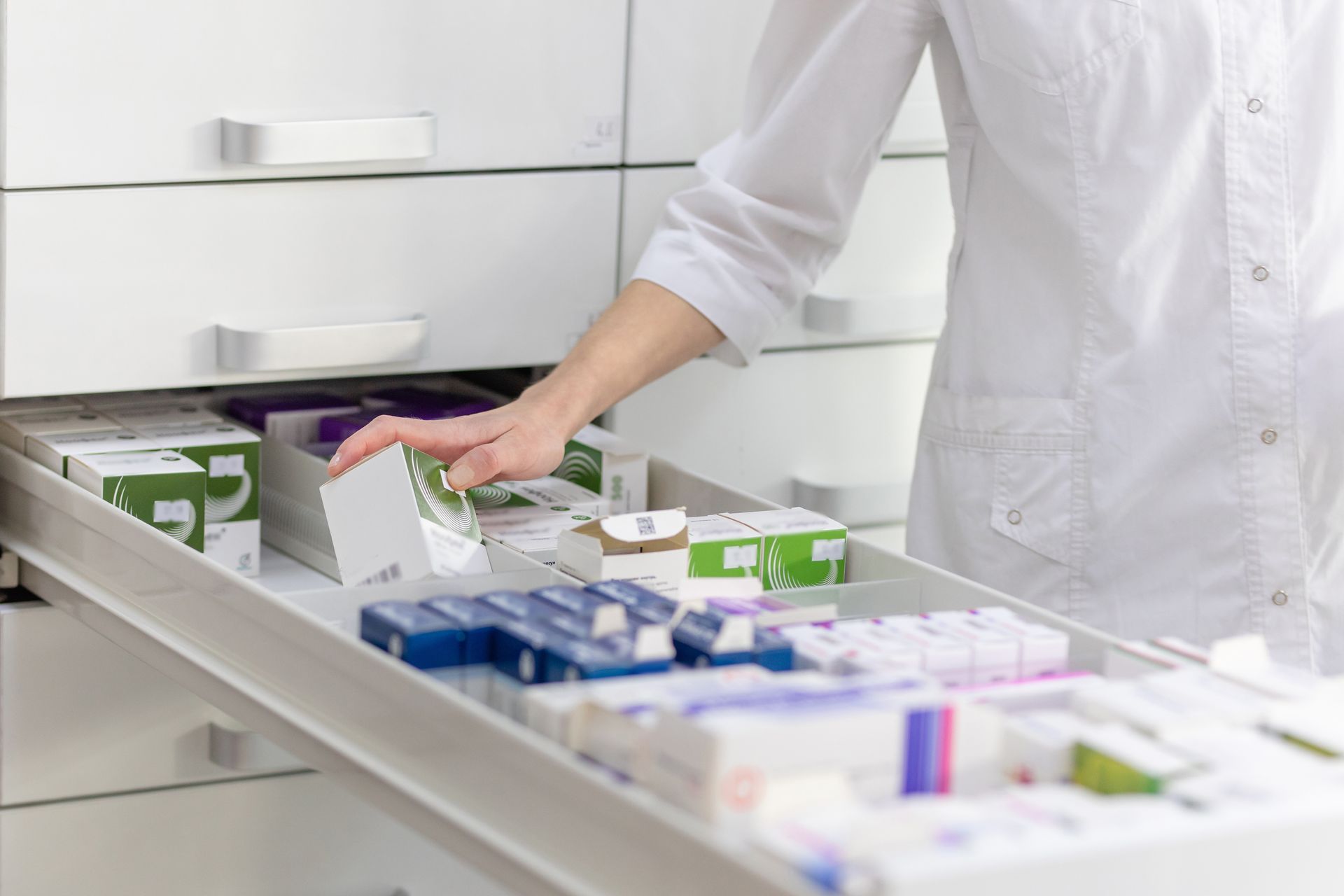 Silhouette de pharmacien qui récupère une boîte de médicaments dans un tiroir