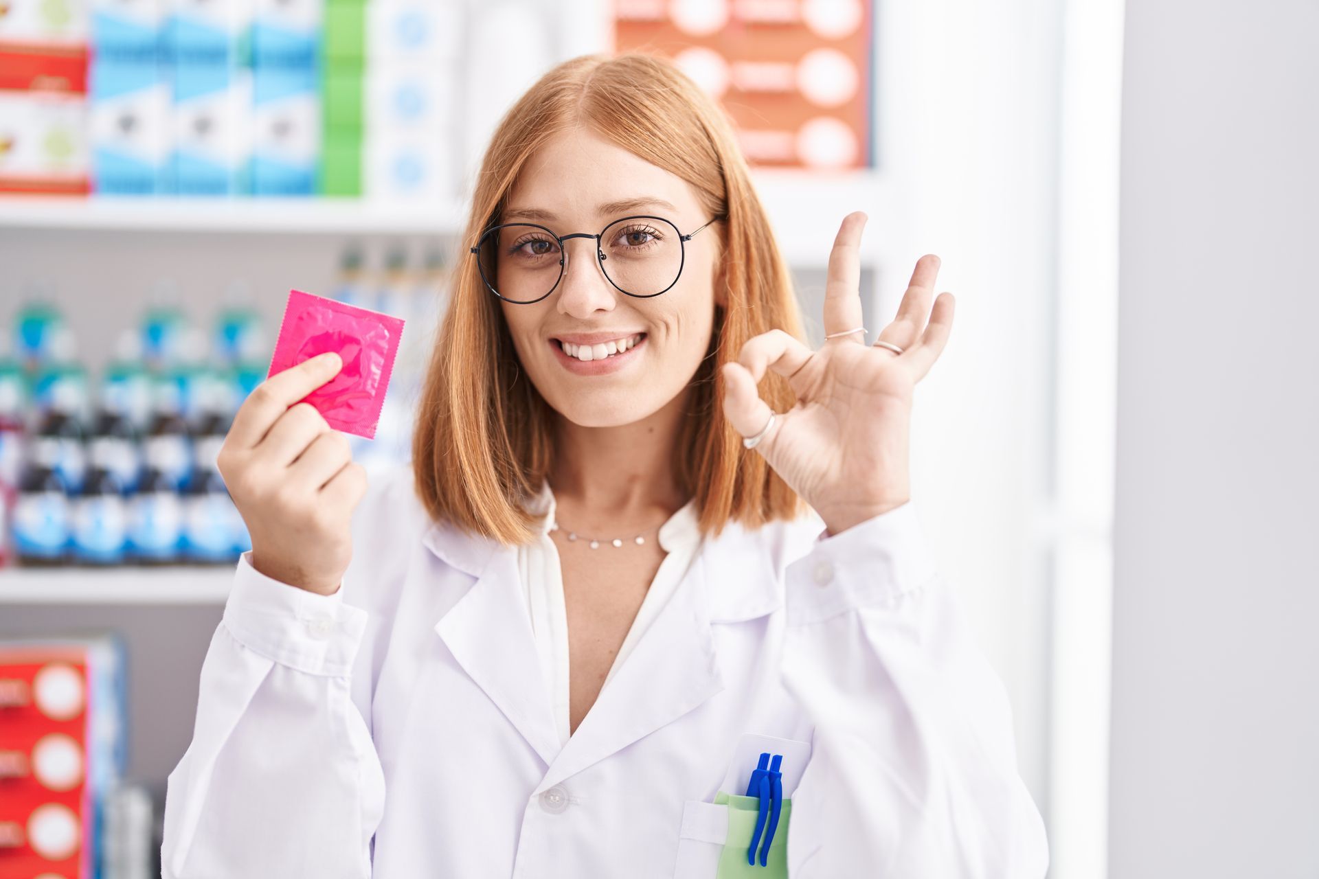 Pharmacienne qui tient un préservatif à l'emballage rose dans une main