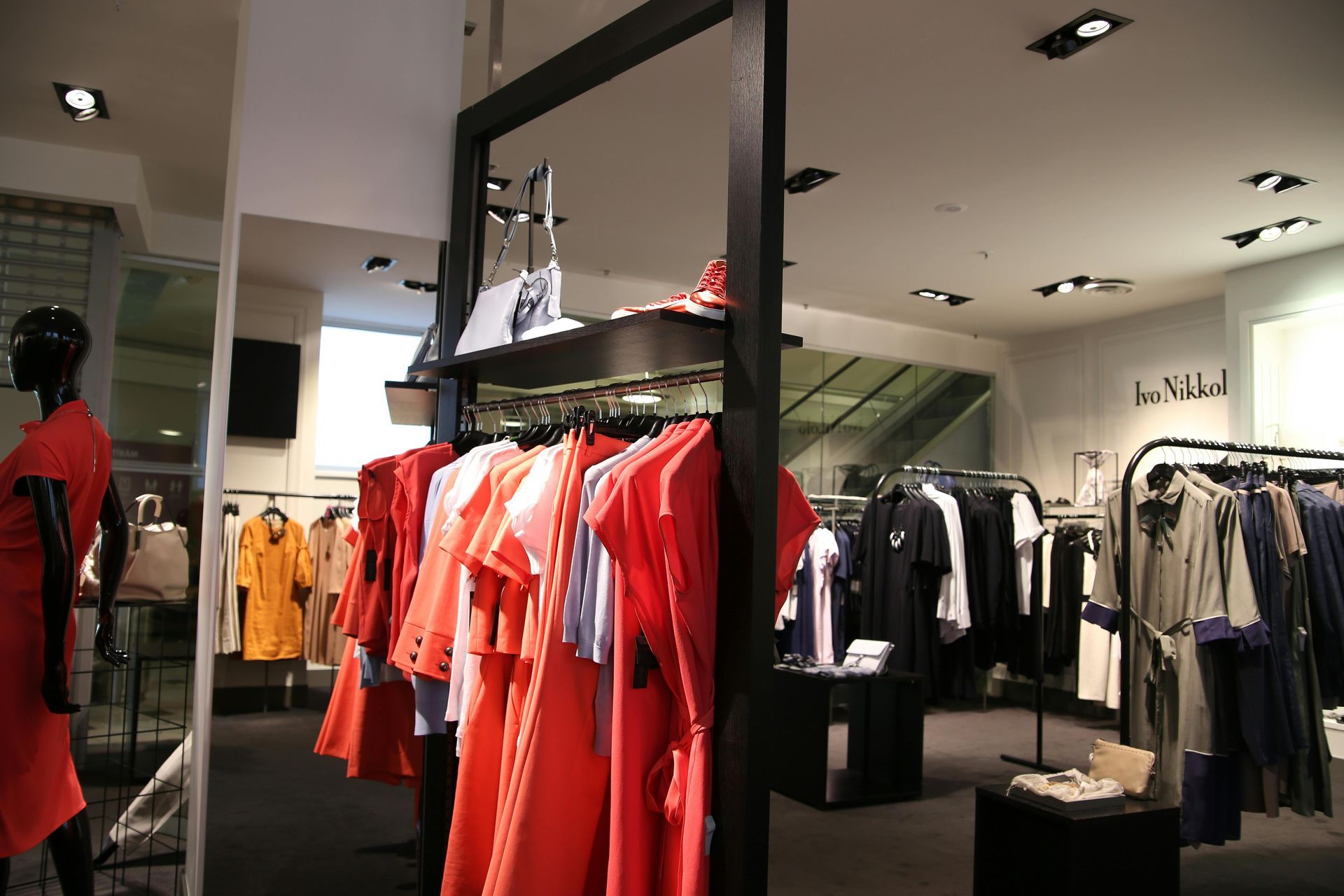 Una donna con un vestito rosso è in piedi in un negozio di abbigliamento