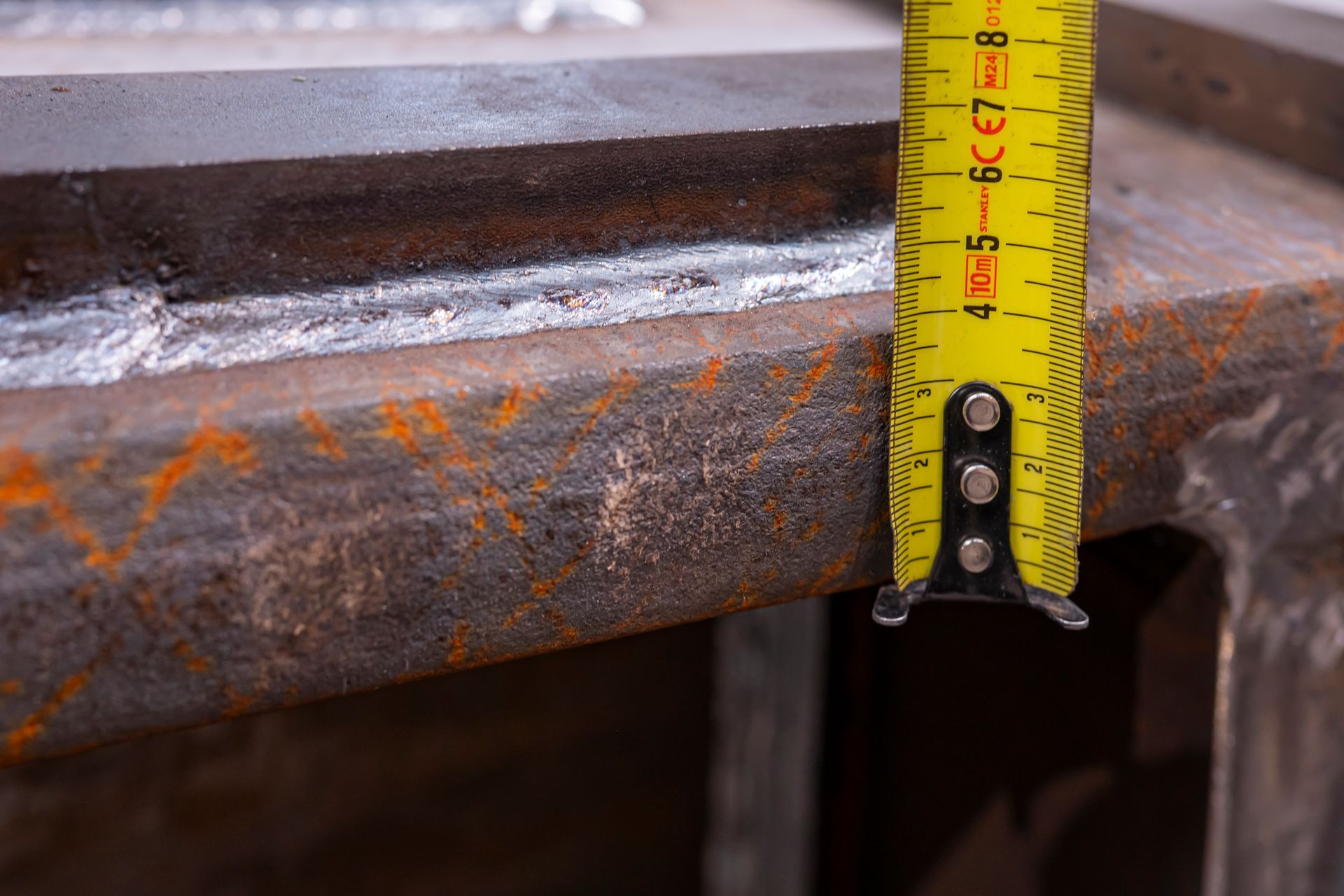 Un mètre ruban est placé à côté d'une structure métallique soudée ; la mesure indique un peu moins de 4 pouces.