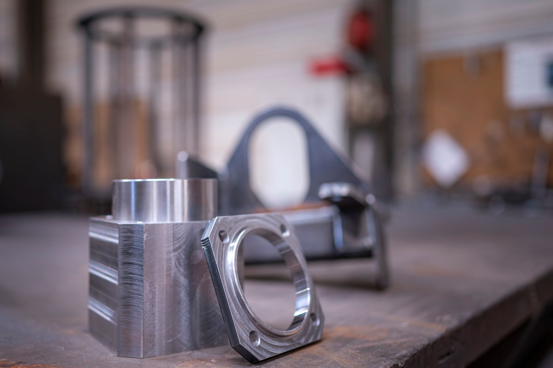Gros plan sur trois pièces métalliques usinées sur un établi dans un atelier.