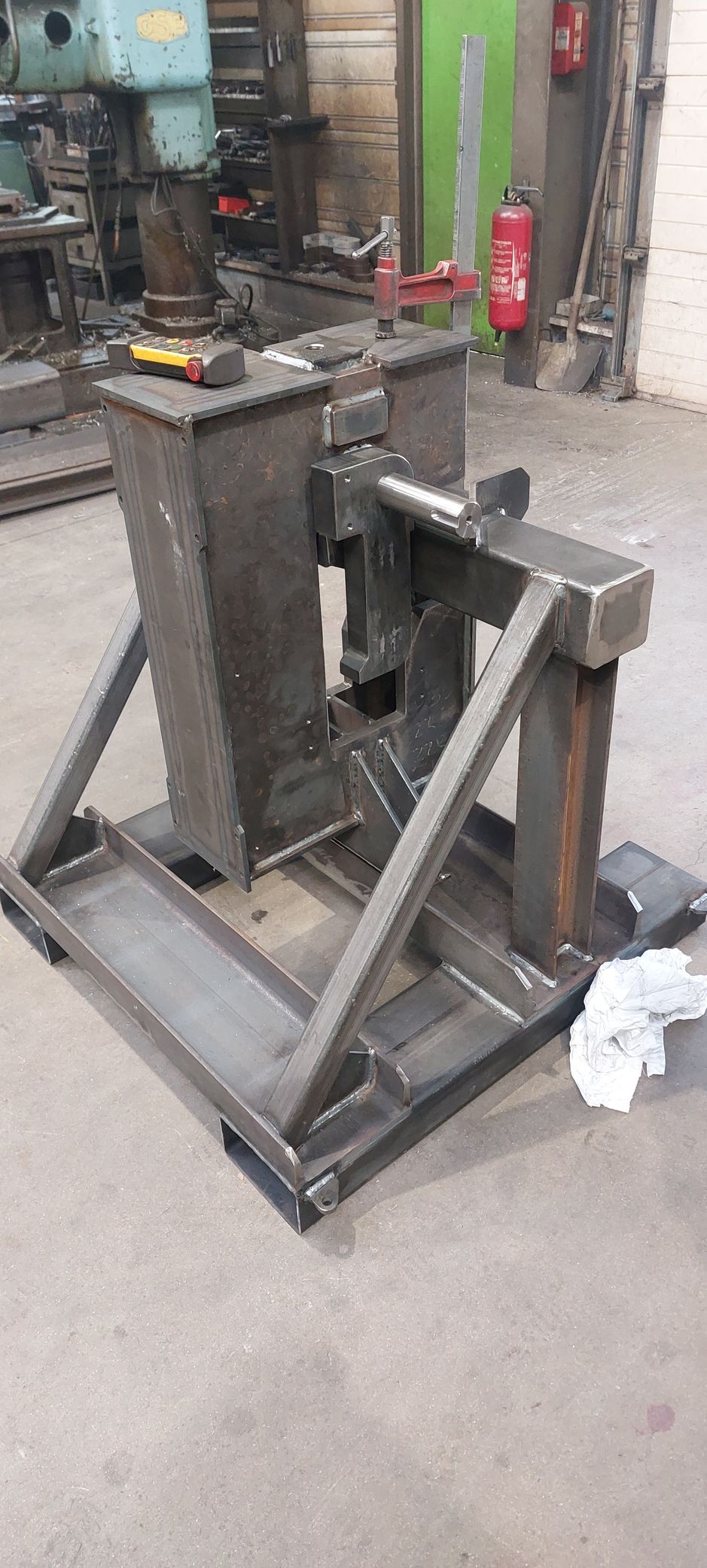 Une machine de fabrication métallique, construite en acier soudé, est posée sur le sol d'un atelier.