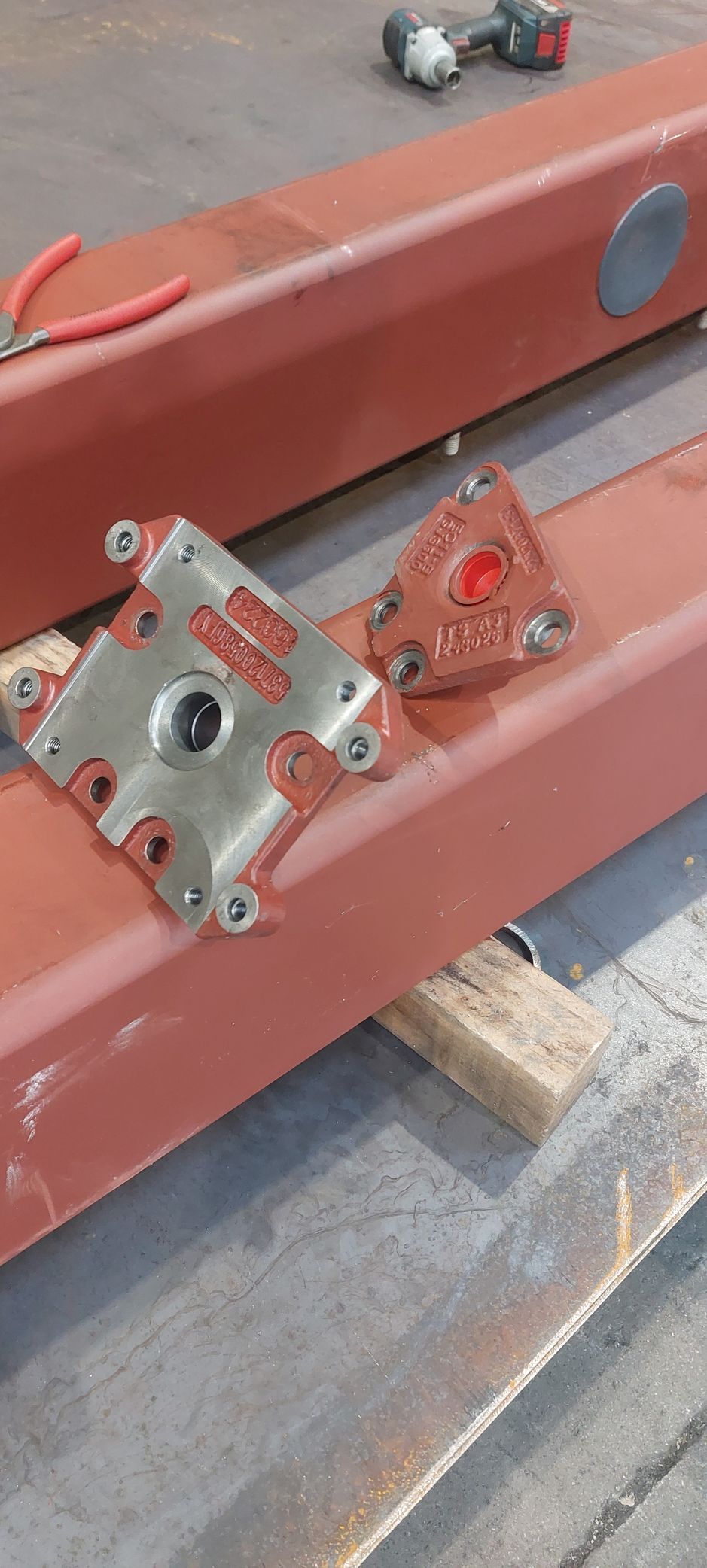 Deux pièces métalliques rouges avec des outils et des barres rouges sur une surface grise.