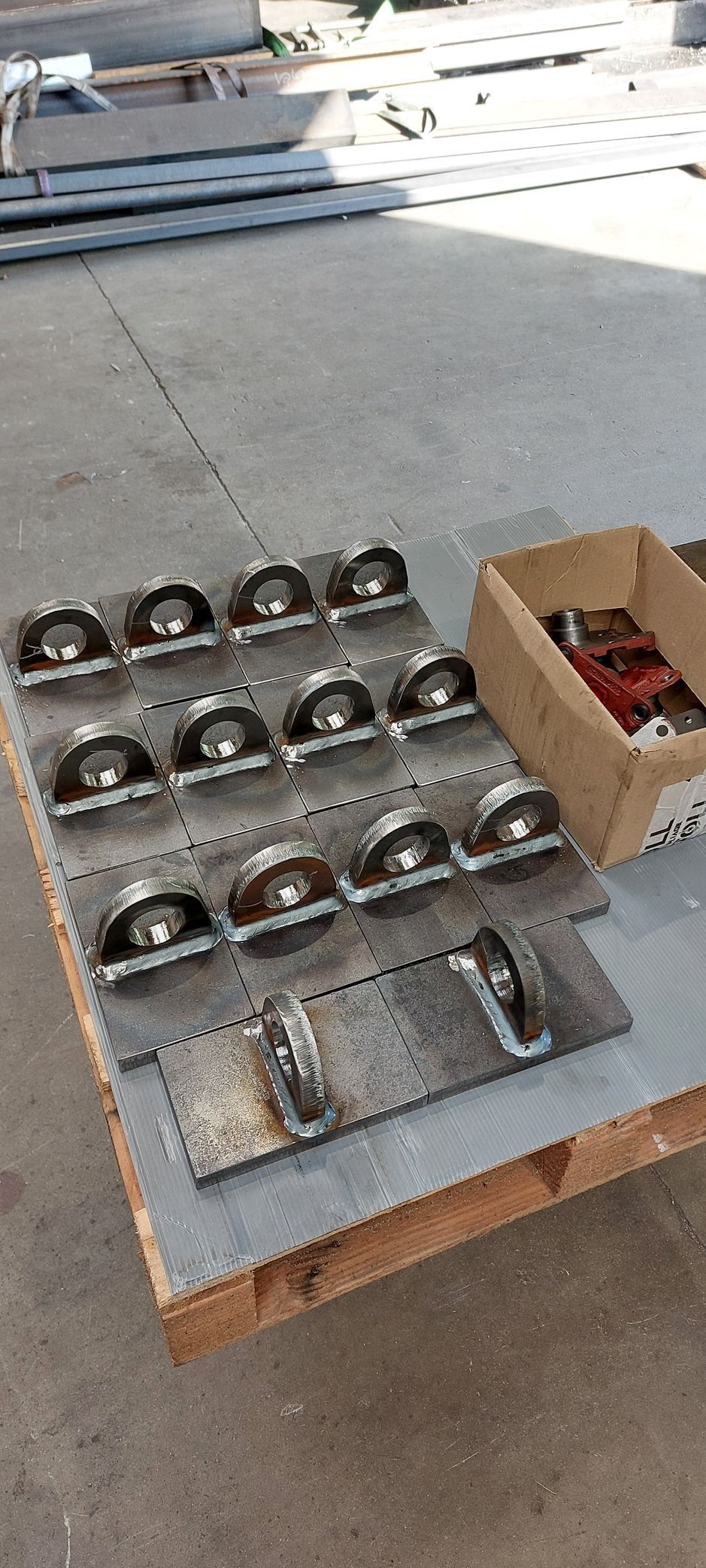 Supports métalliques avec poulies sur une palette en bois à côté d'une boîte en carton.