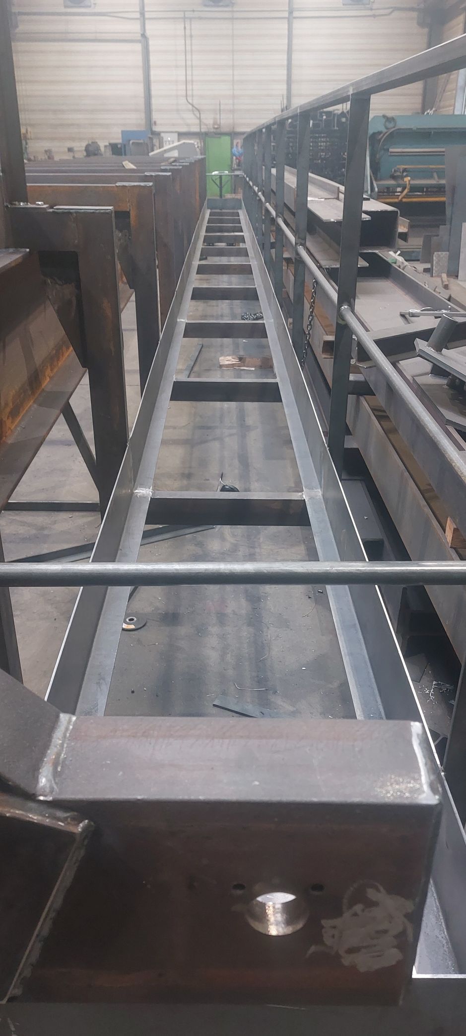 Structure métallique avec poutres parallèles et entretoises s'étendant au loin, pouvant servir de passerelle ou de convoyeur.