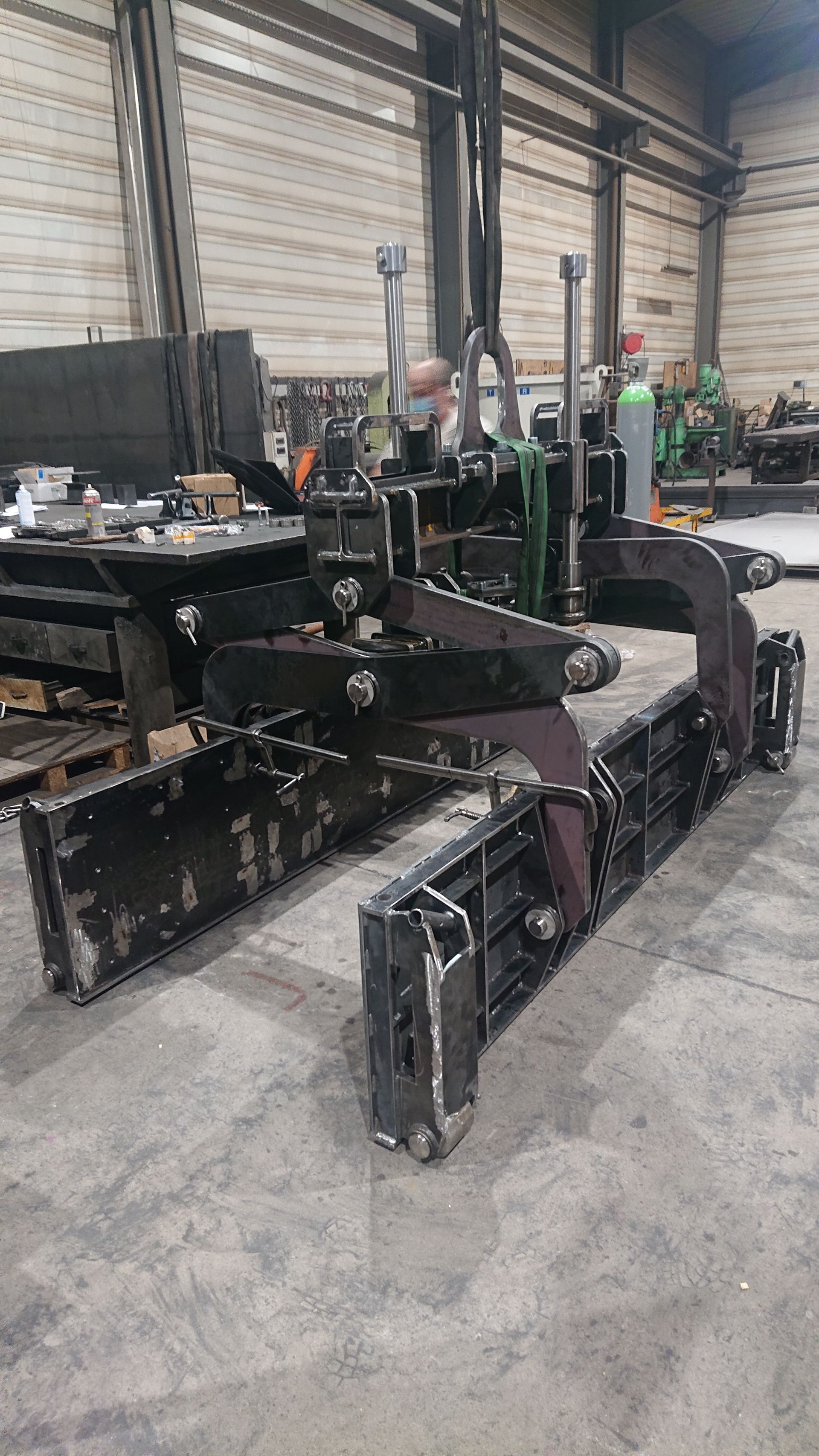 Pince industrielle en métal noir dans un atelier, utilisée pour soulever et déplacer des objets lourds.