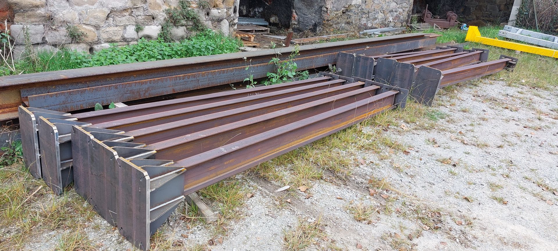 Un tas de poutres métalliques rouillées sur un sol herbeux.