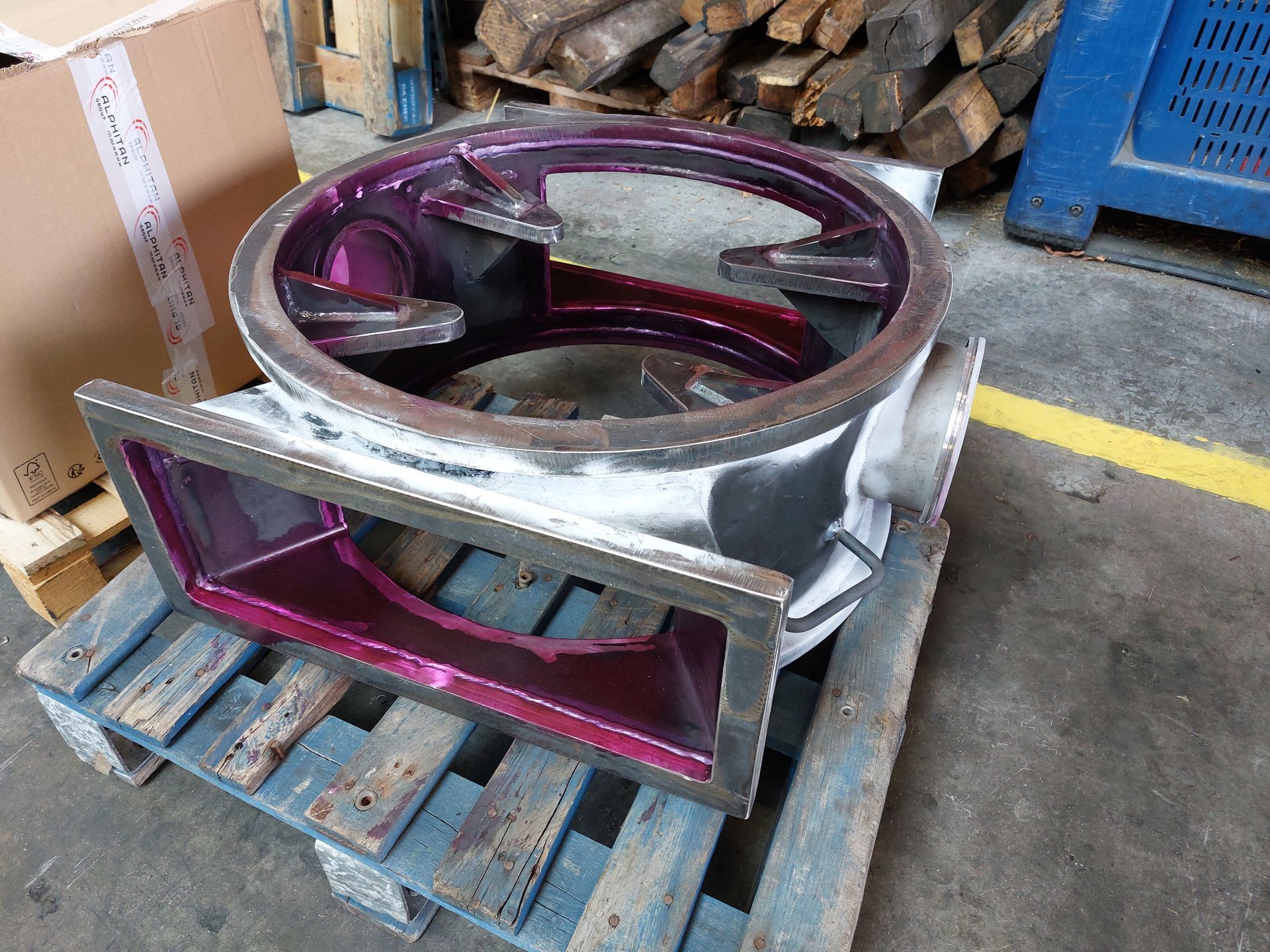 Pièce industrielle à l'intérieur violet, posée sur une palette en bois.