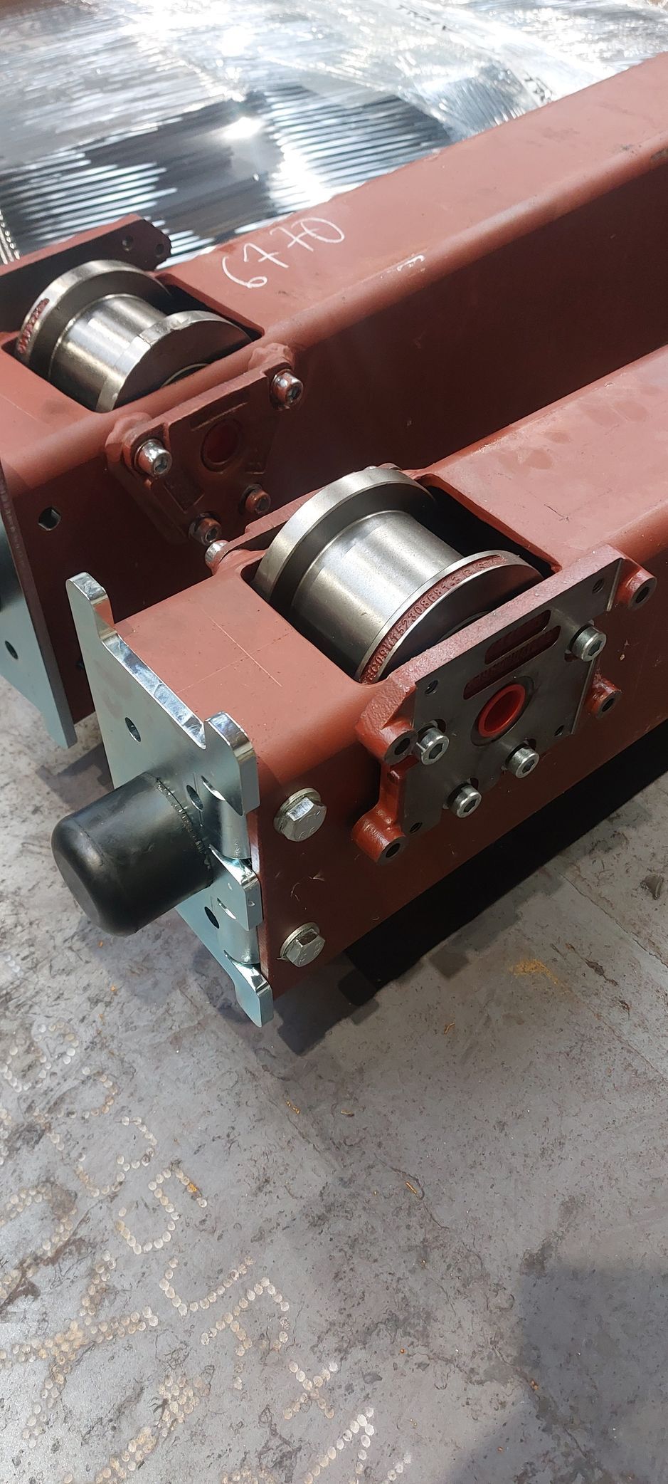 Deux poutres métalliques brun rougeâtre munies de rouleaux, faisant peut-être partie d'une grue ou d'une autre machine industrielle.