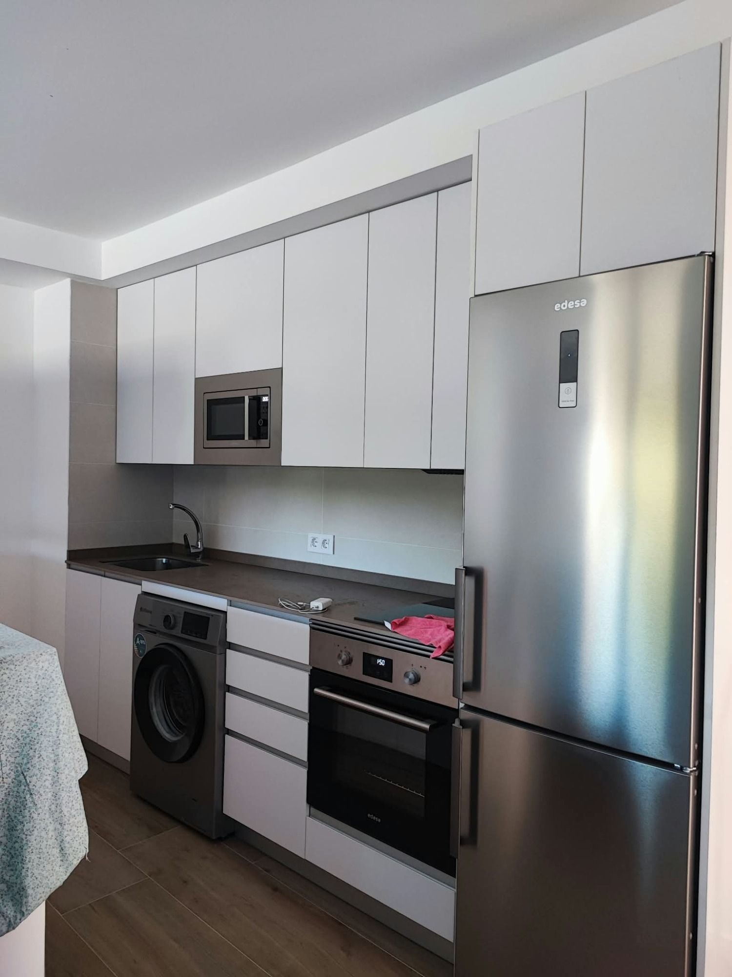 Cocina moderna blanca con electrodomésticos de acero inoxidable y encimeras oscuras