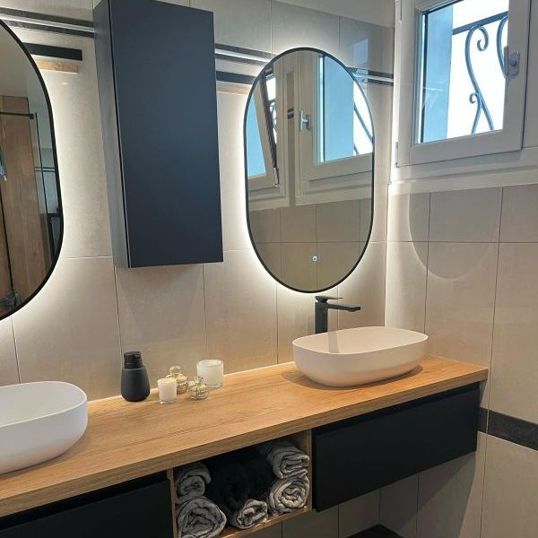 Deux vasques sur un meuble en bois et deux miroirs lumineux